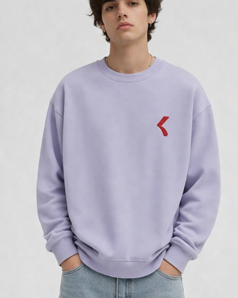 man wearing lavender sweatshirt with KRPA logo on it standing on a plain background