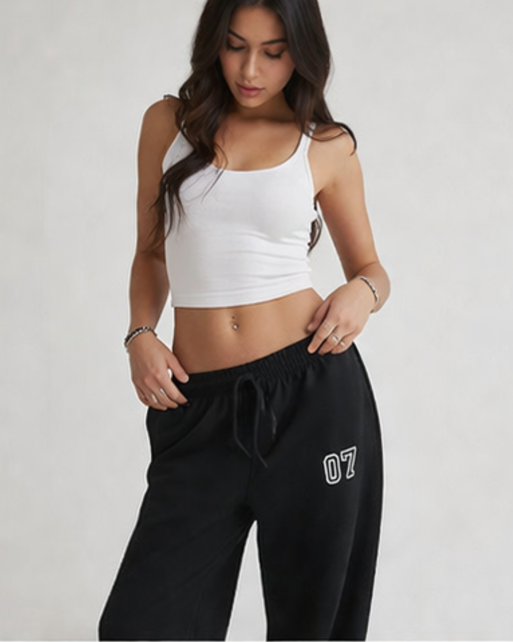 Woman wearing a white crop top and black pants with '07' on a plain background