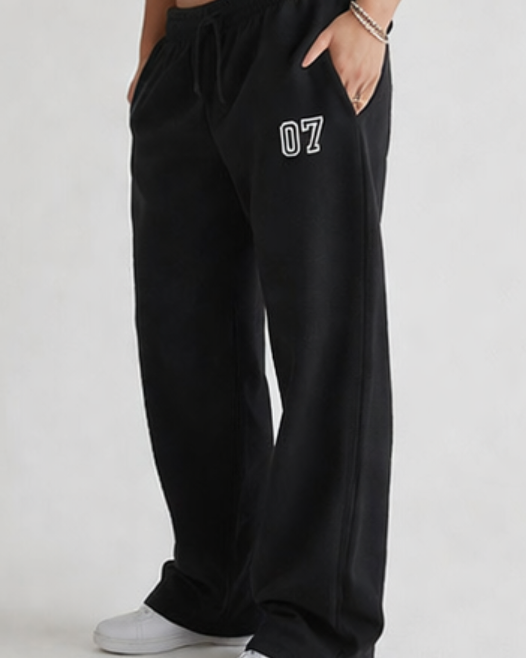 Person wearing black sweatpants with '07' on a plain background