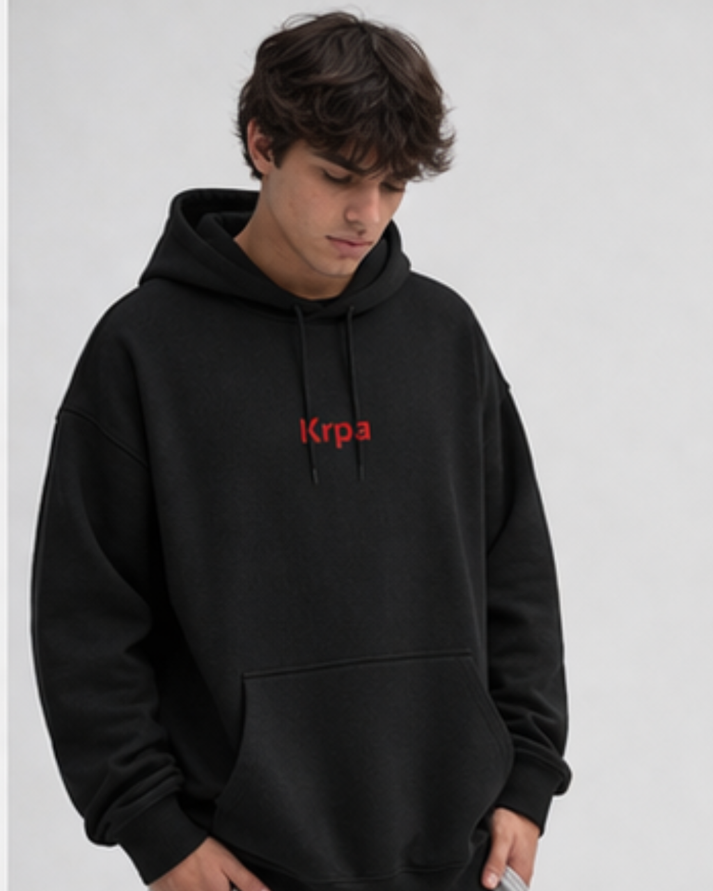 Person wearing a black hoodie with red KRPA logo on a light gray background