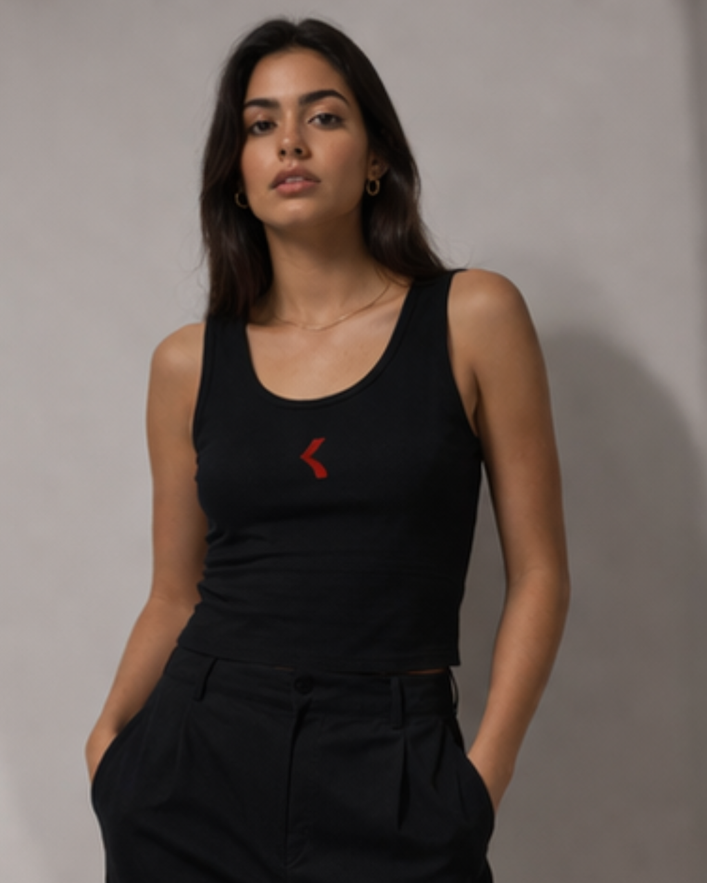 Woman wearing a black tank top with krpa logo against a plain background