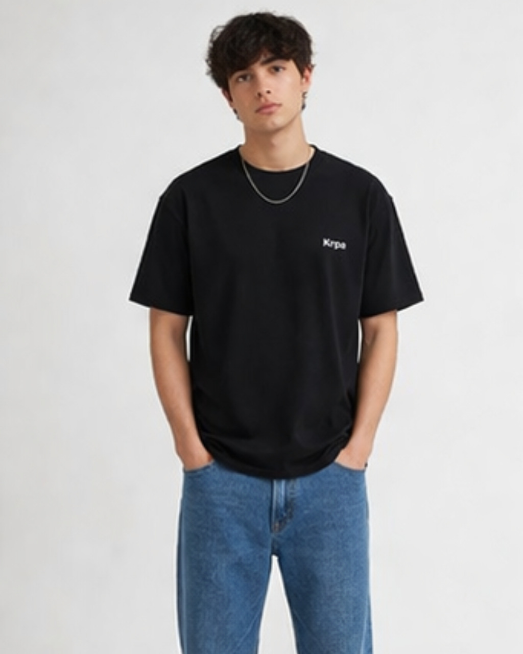 Person wearing a black t-shirt with krpa logo and blue jeans on a white background