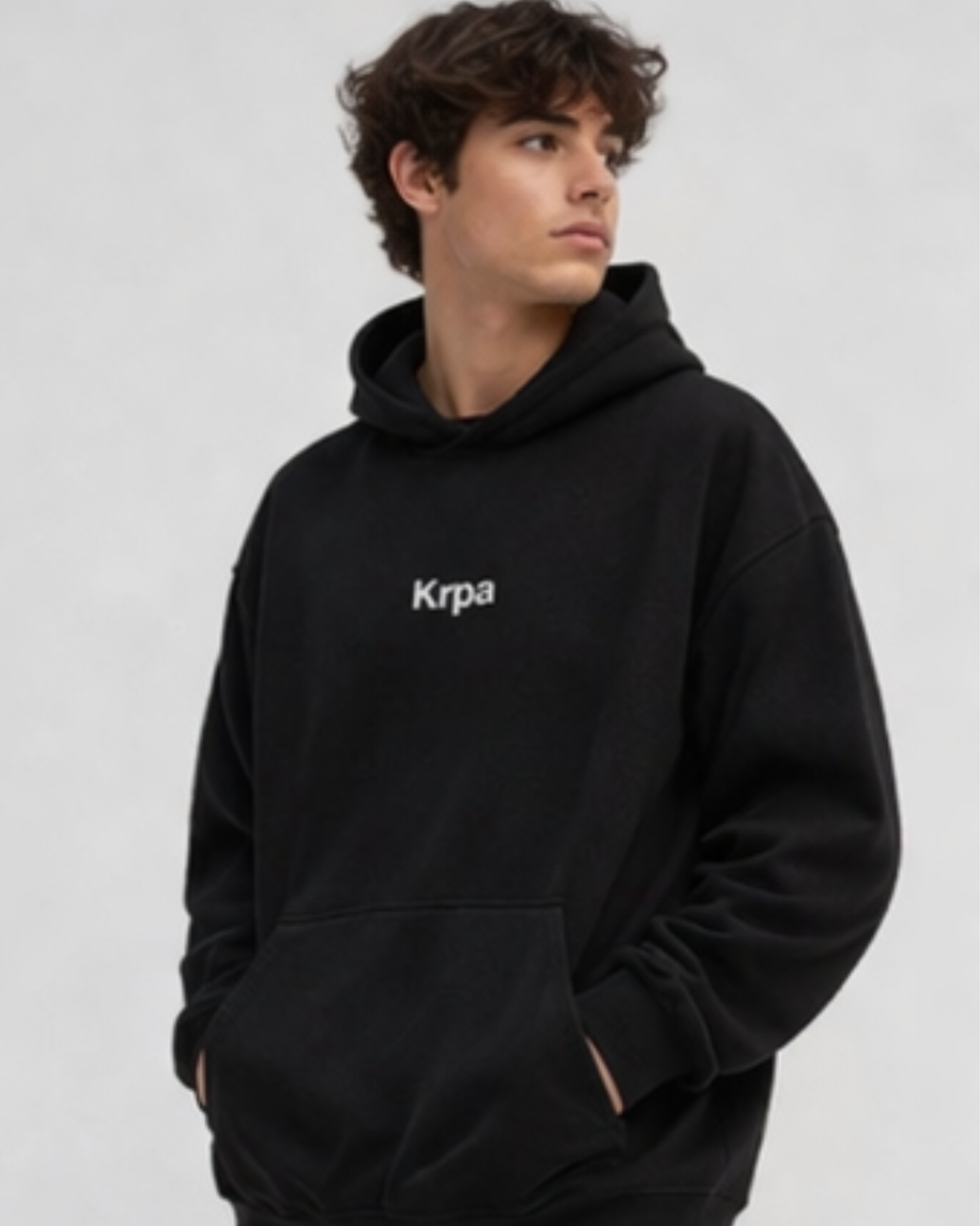 Person wearing a black hoodie with 'Krpa' logo on a light gray background