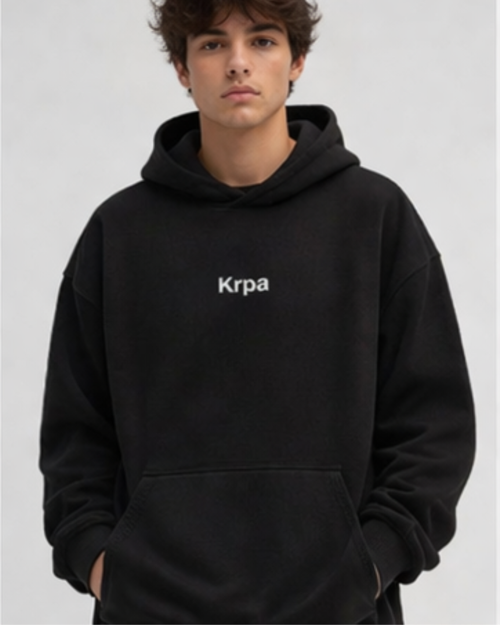 Person wearing a black hoodie with 'Krpa' logo on a light gray background