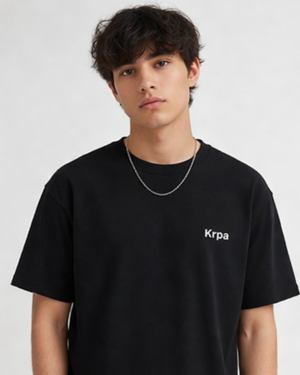 Person wearing a black t-shirt with 'Krpa' logo on a plain background