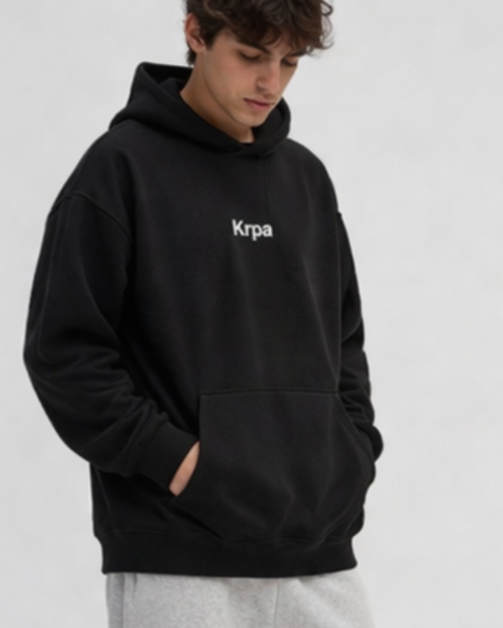 Person wearing a black hoodie with 'Krpa' logo on a white background