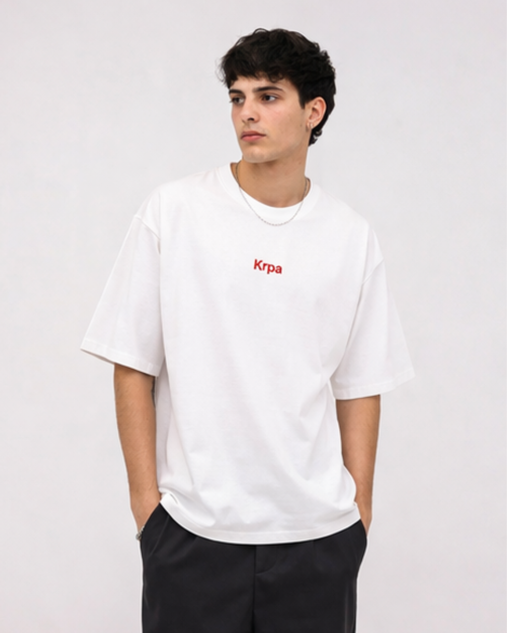 Person wearing a white t-shirt with krpa logo on a plain background