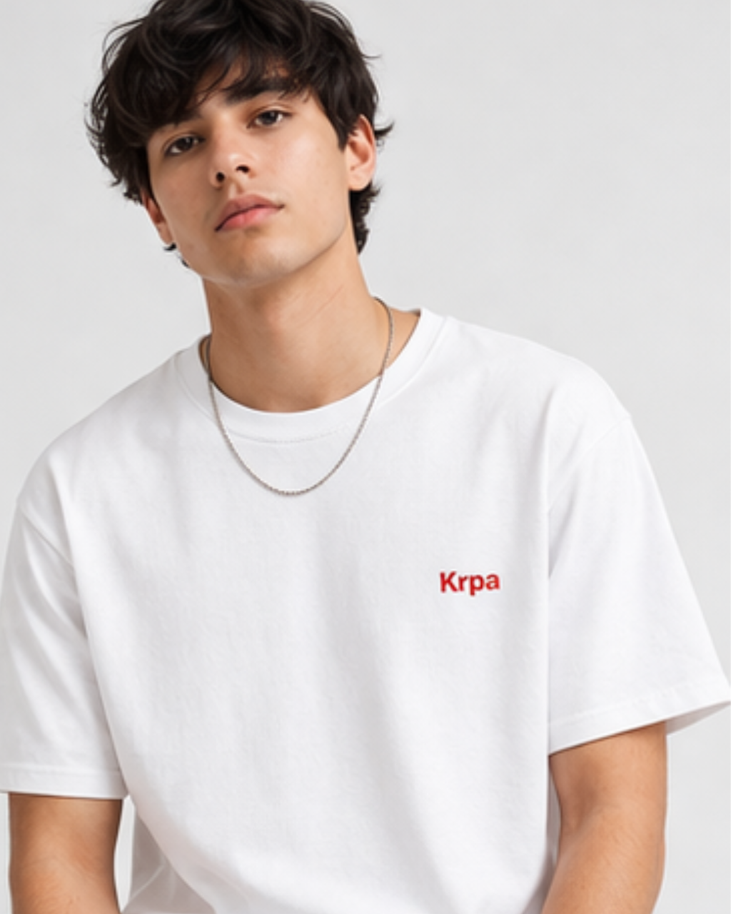 Person wearing a white t-shirt with 'Krpa' logo on a plain background
