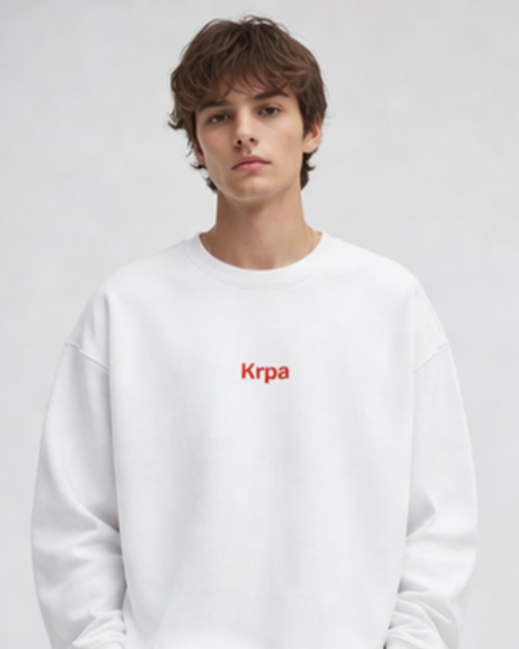 Person wearing a white sweatshirt with 'Krpa' logo on a plain background