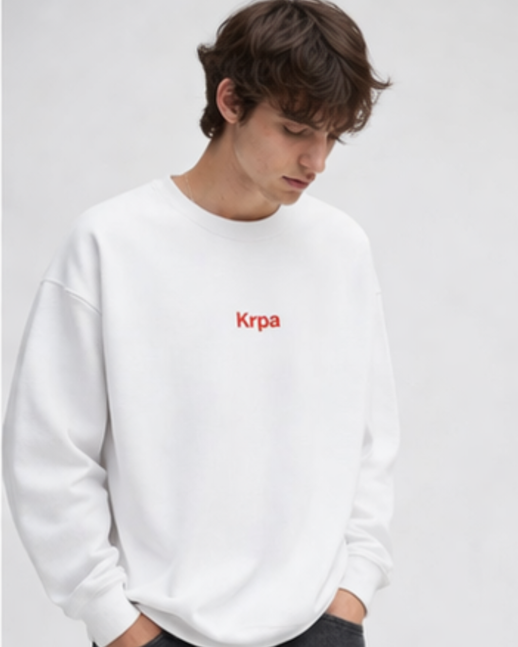 Person wearing a white sweatshirt with 'Krpa' logo on a light gray background