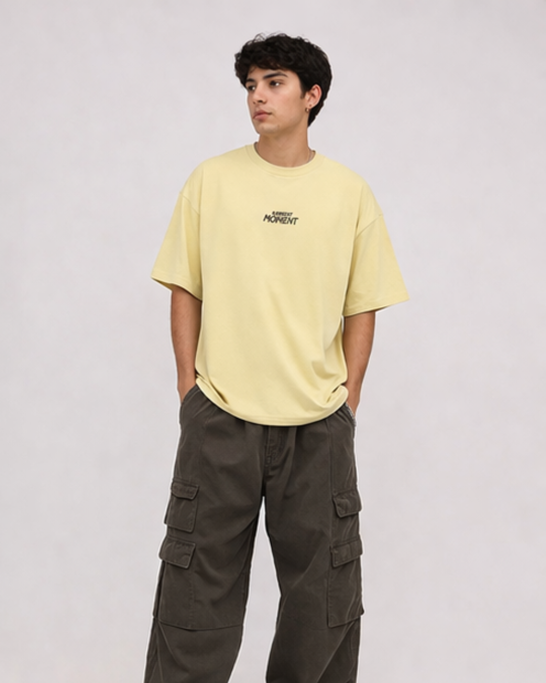 Person wearing a light yellow t-shirt and dark cargo pants on a white background