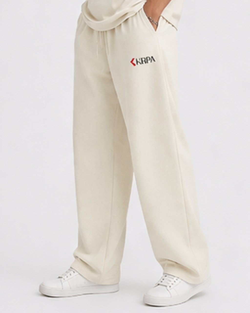 Person wearing off white sweatpants with KRPA logo on a white background