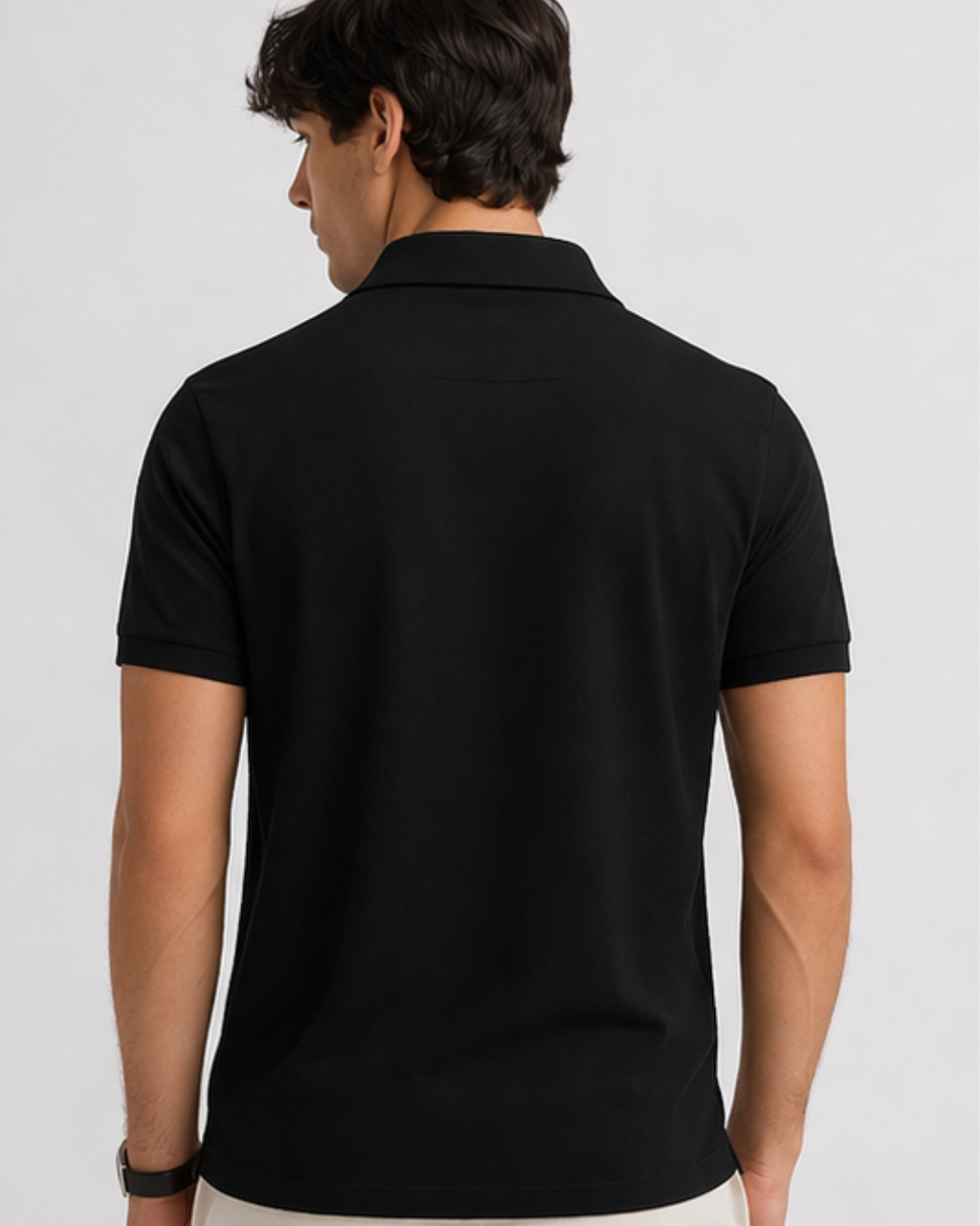 Person wearing a black polo shirt on a light gray background