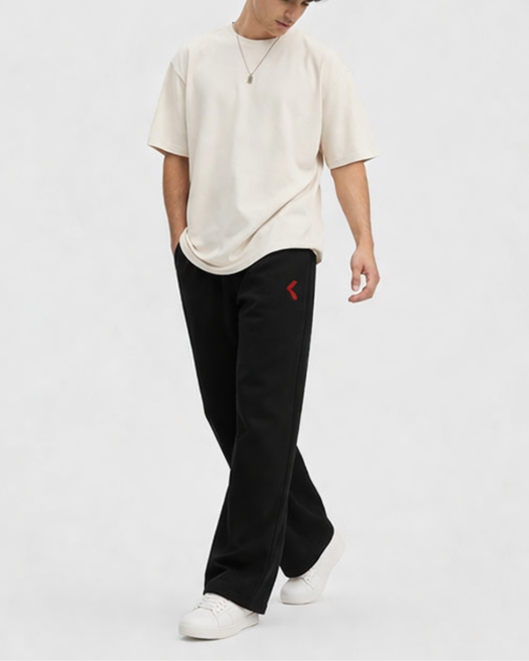 Person wearing a beige oversized shirt and black pants with KRPA logo on a white background