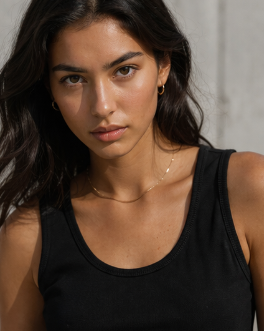Woman wearing a black tank top with a neutral background