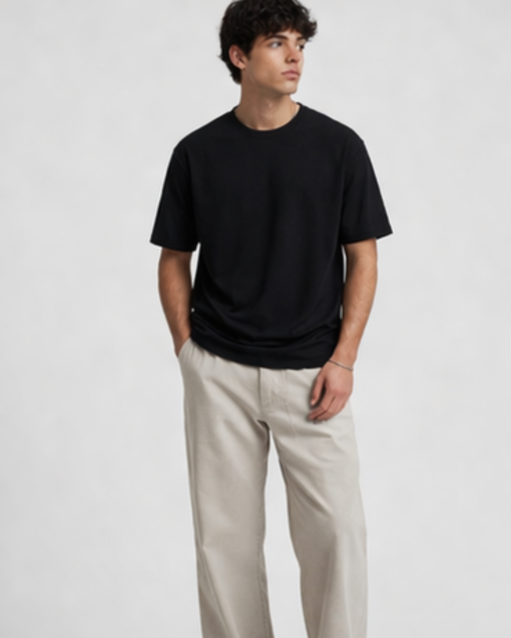 Person wearing a black t-shirt and beige pants on a white background