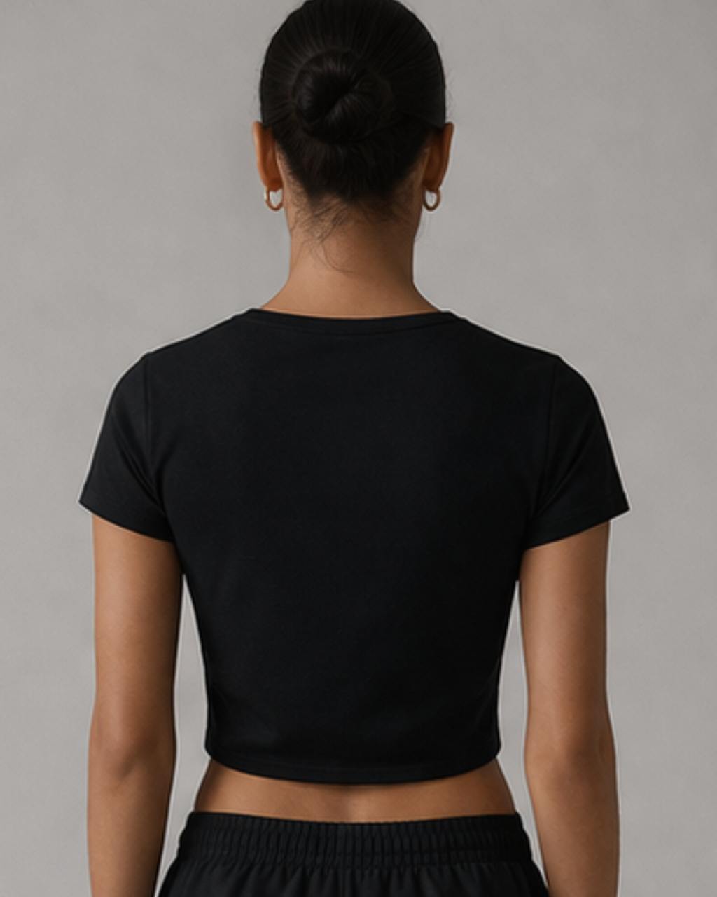Person wearing a black crop top against a gray background