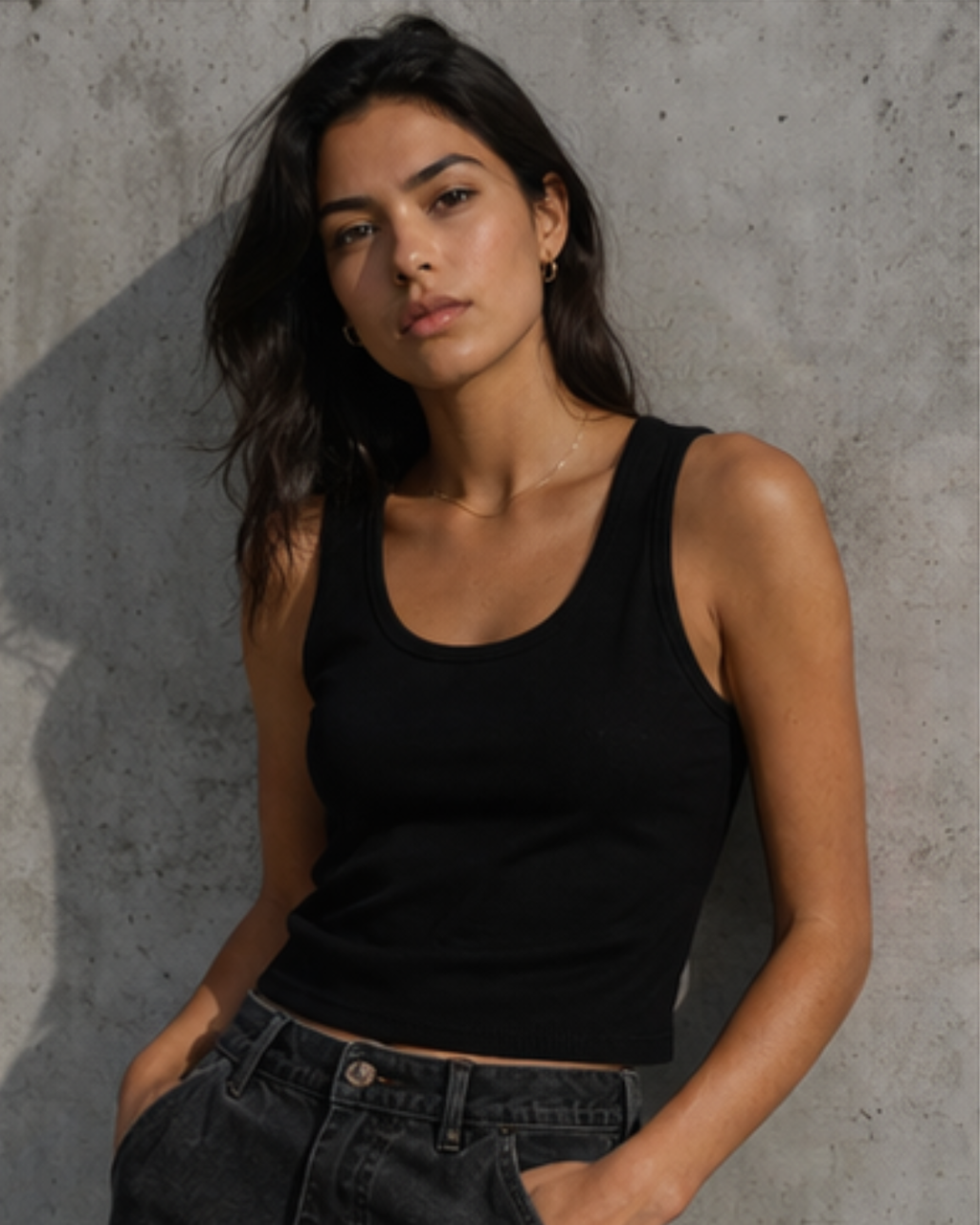 Woman wearing a black tank top against a concrete wall
