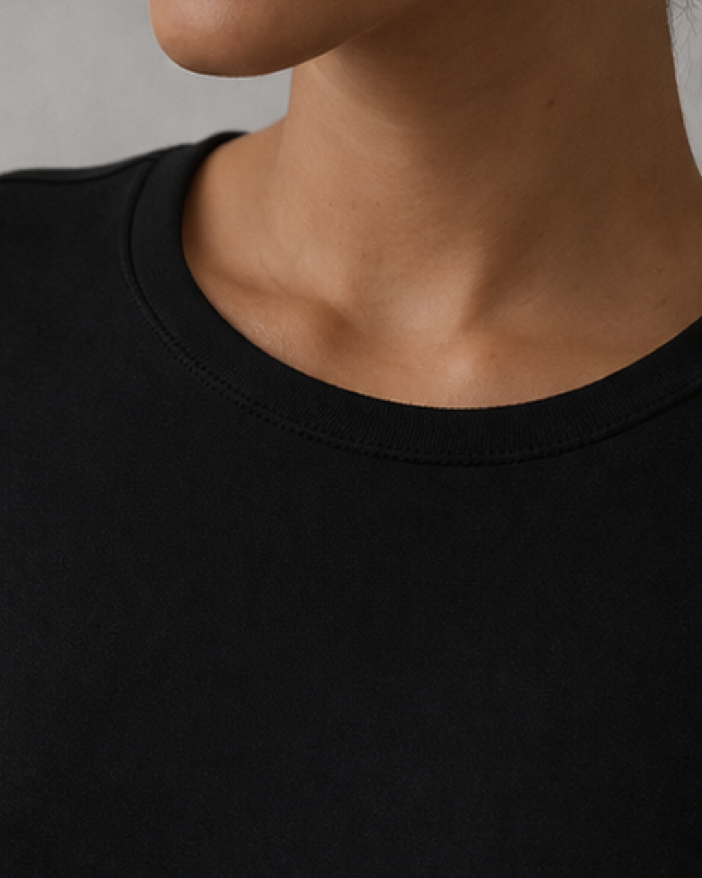 Close-up of a person wearing a black t-shirt against a neutral background