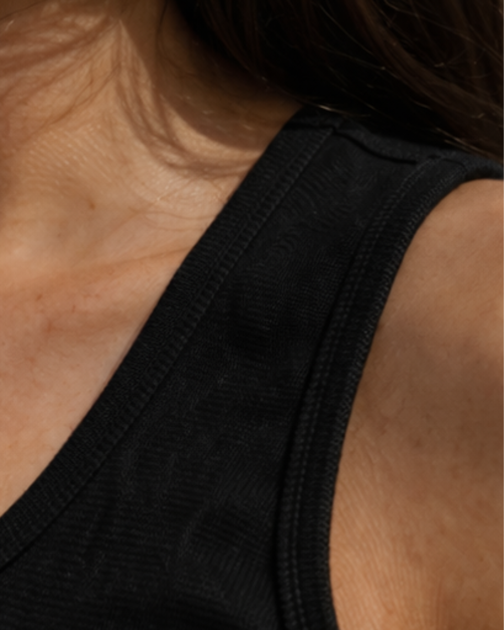 Close-up of a person wearing a black tank top with a blurred background