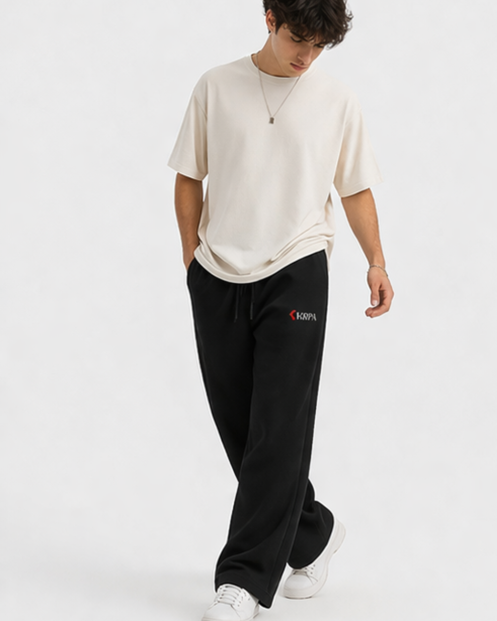 Person wearing a white oversized shirt and black pants with KRPA logo on a white background