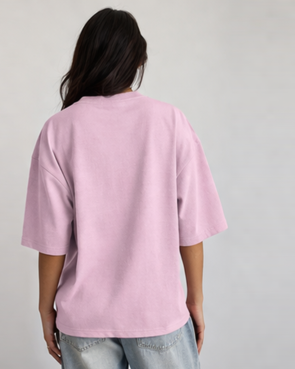 Person wearing a pink t-shirt and light blue jeans on a plain background