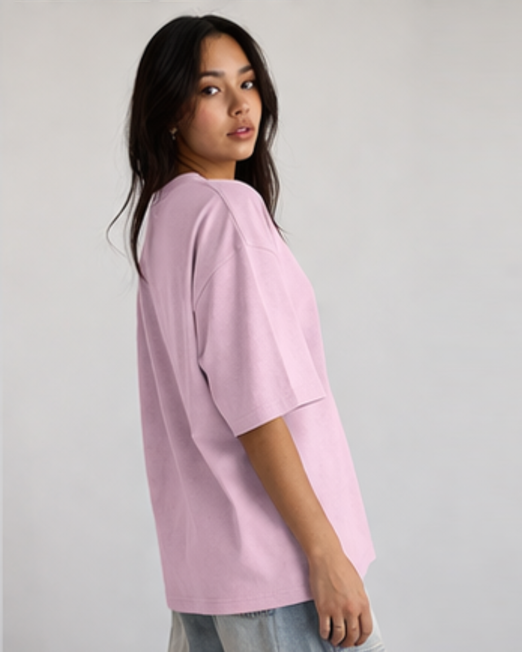 Woman wearing a light pink oversized shirt on a plain background