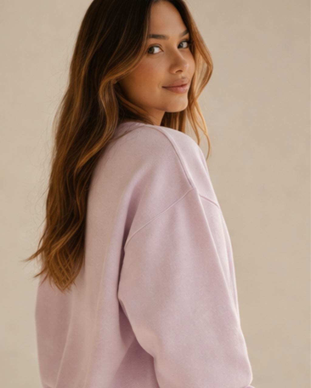 Woman wearing a light pink sweater against a beige background