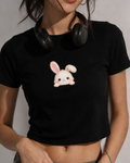 Person wearing a black crop top with a cute rabbit design and headphones on a neutral background