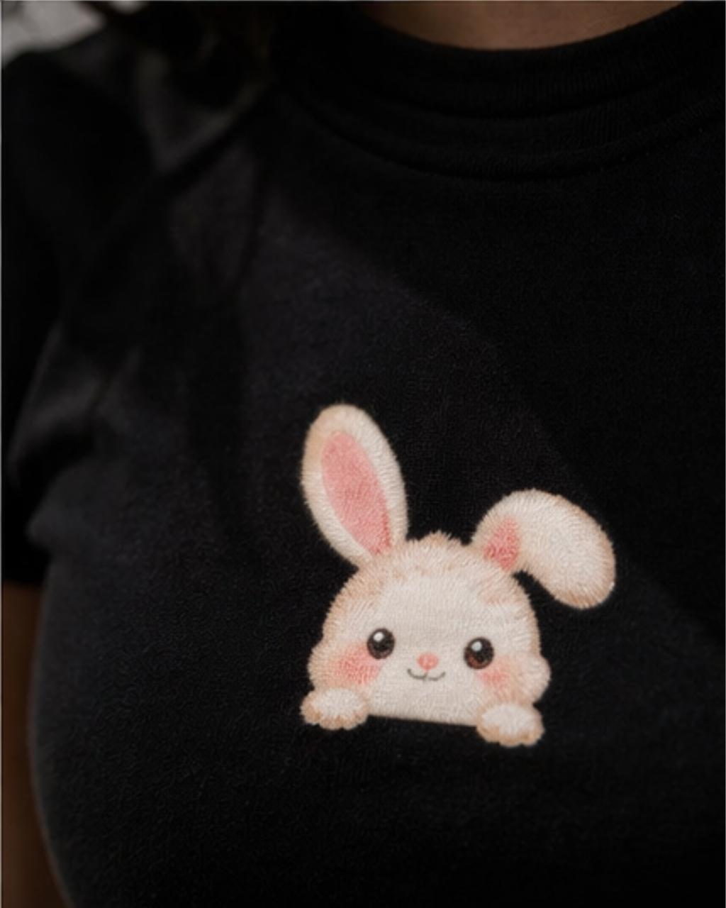 Black sweater with a cute printed bunny design on a dark background.