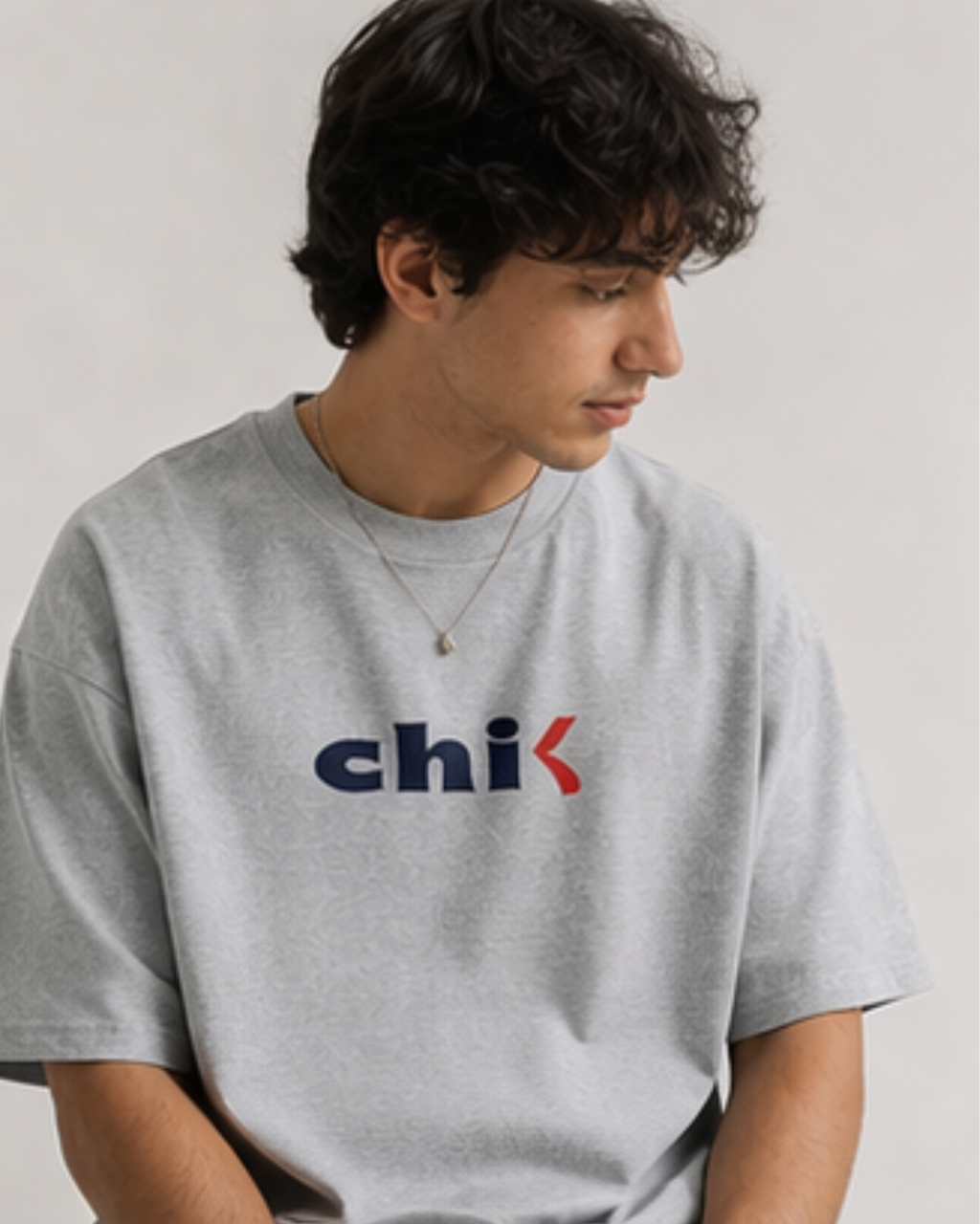 Person wearing a gray t-shirt with 'chi-k' logo on a plain background