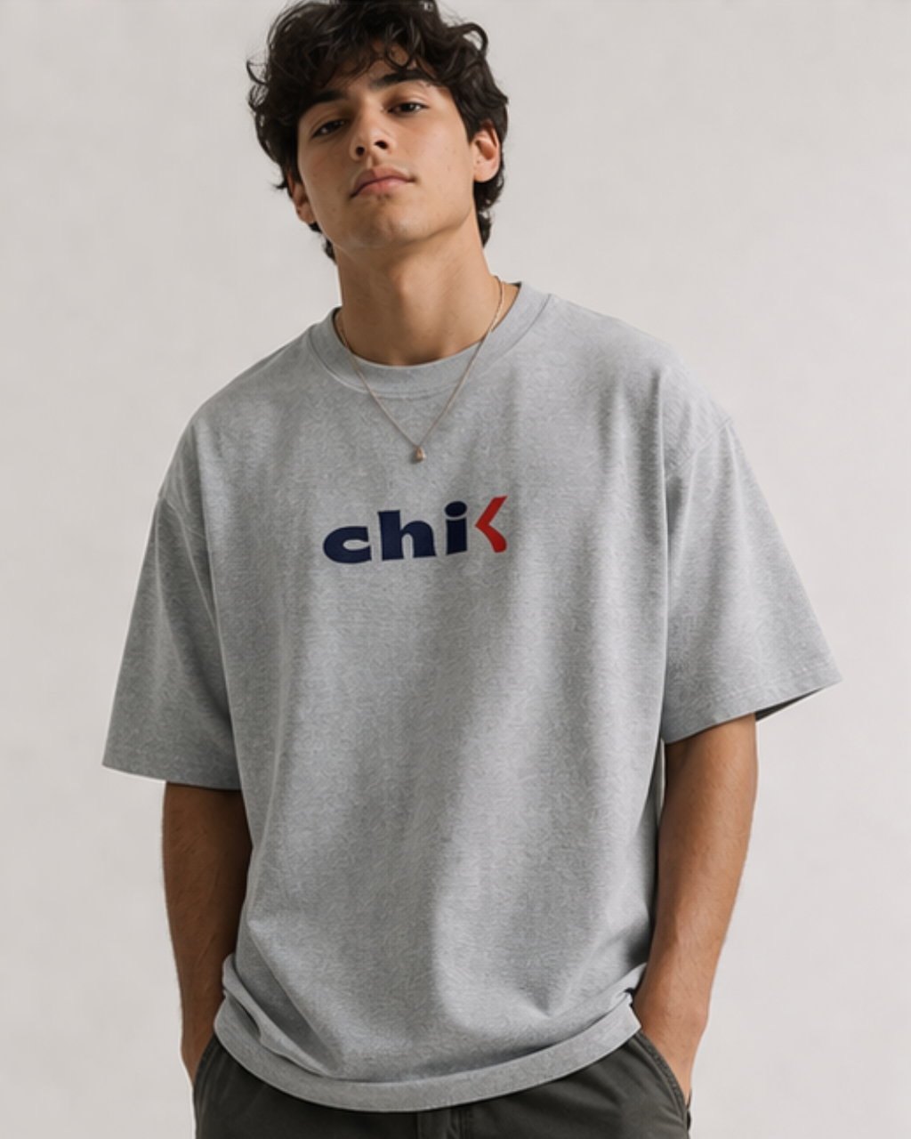 Person wearing a gray t-shirt with a colorful logo on a plain background