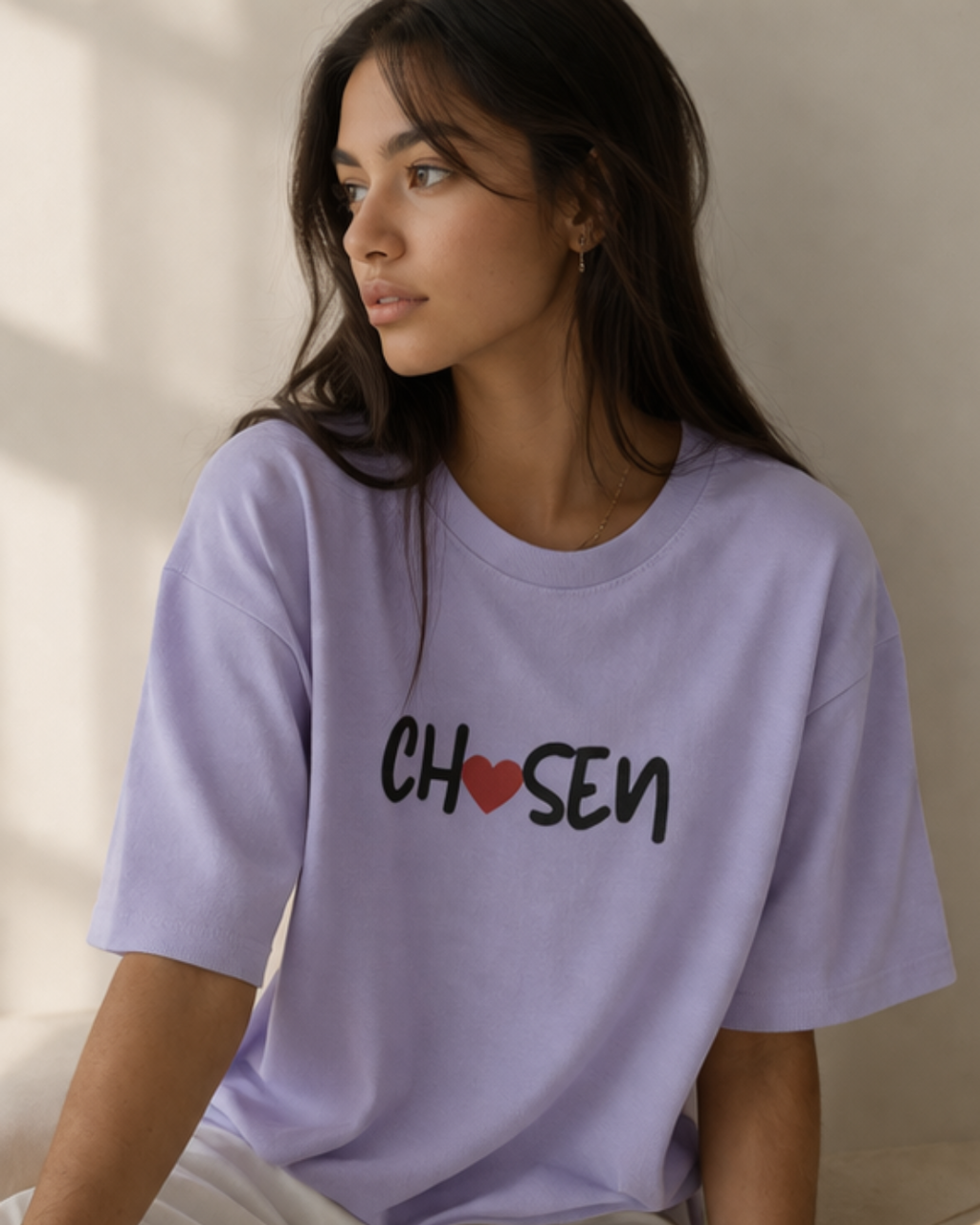 Woman wearing a lavender t-shirt with 'Chosen' printed on it against a neutral background