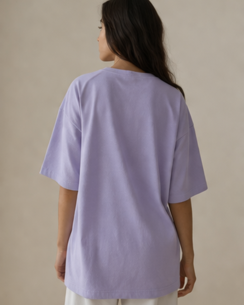Person wearing a lavender oversized t-shirt against a beige background