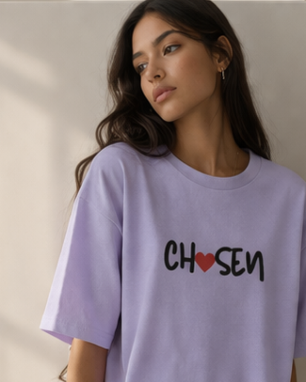 Woman wearing a lavender oversized t-shirt with 'Chosen' printed on it against a neutral background