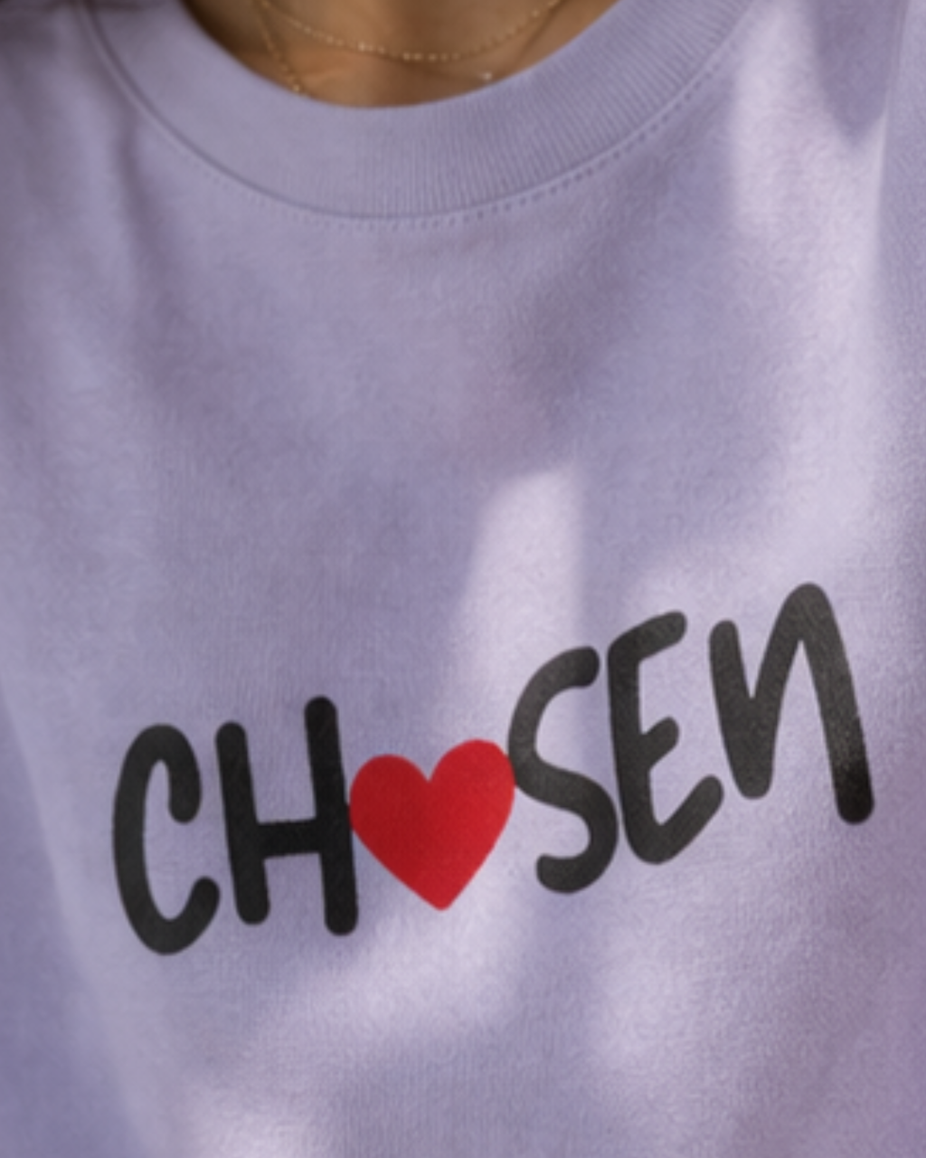 Close-up of lavender cotton oversized t-shirt with 'CHOSEN' text and red heart on a white background