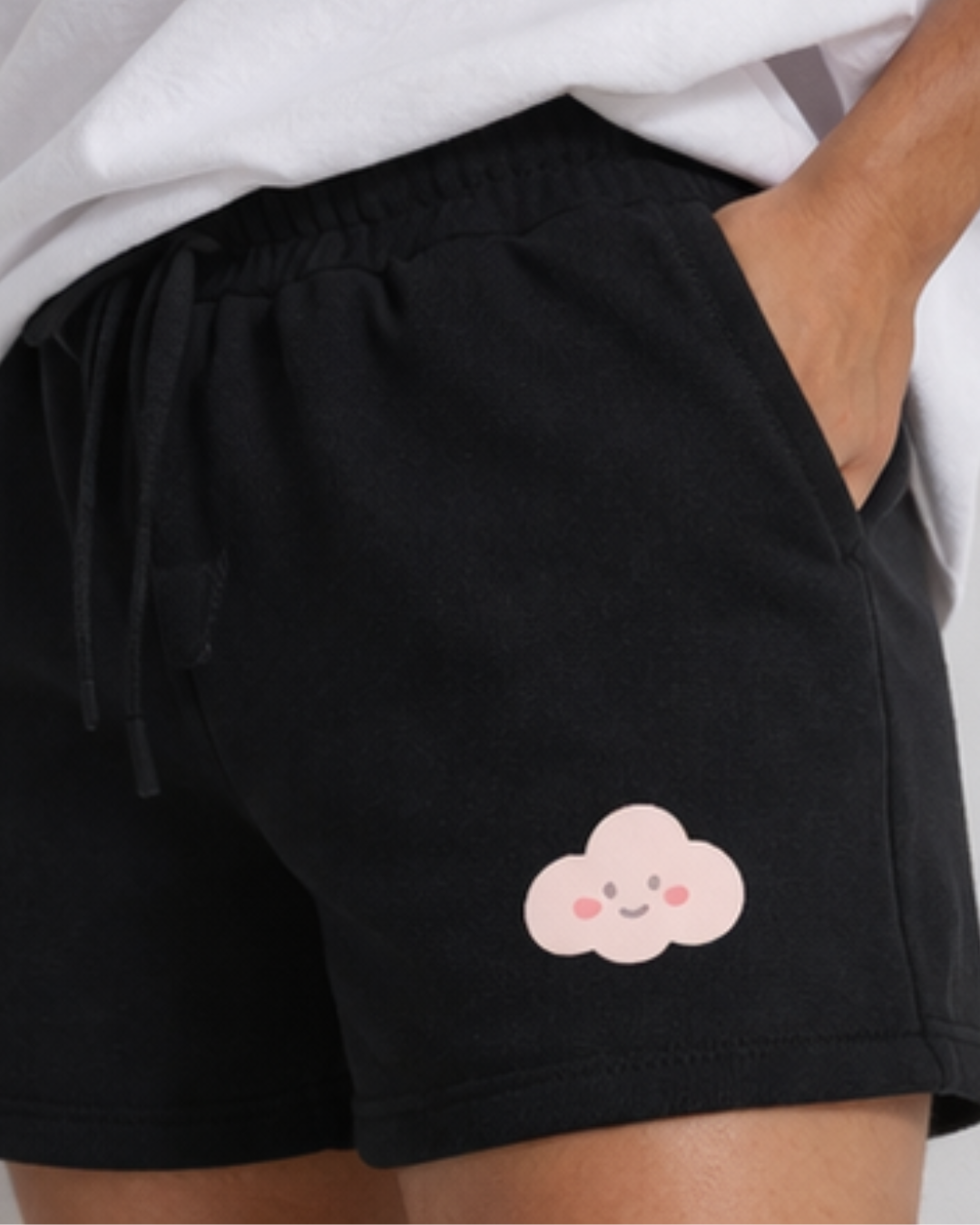 Black shorts with a pink cloud design on a person wearing a white shirt.
