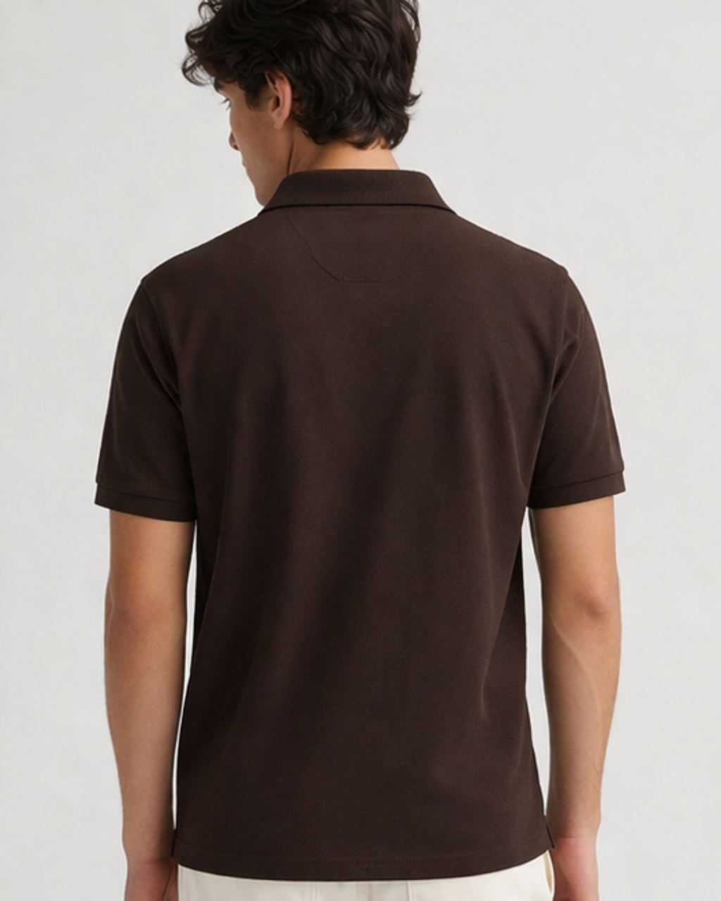 Person wearing a brown polo shirt on a plain background