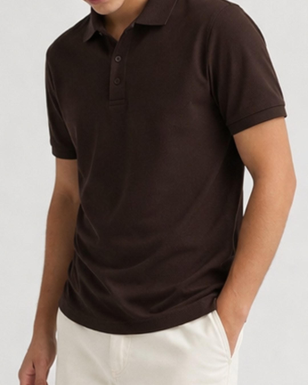 Person wearing a brown polo shirt and white pants on a plain background