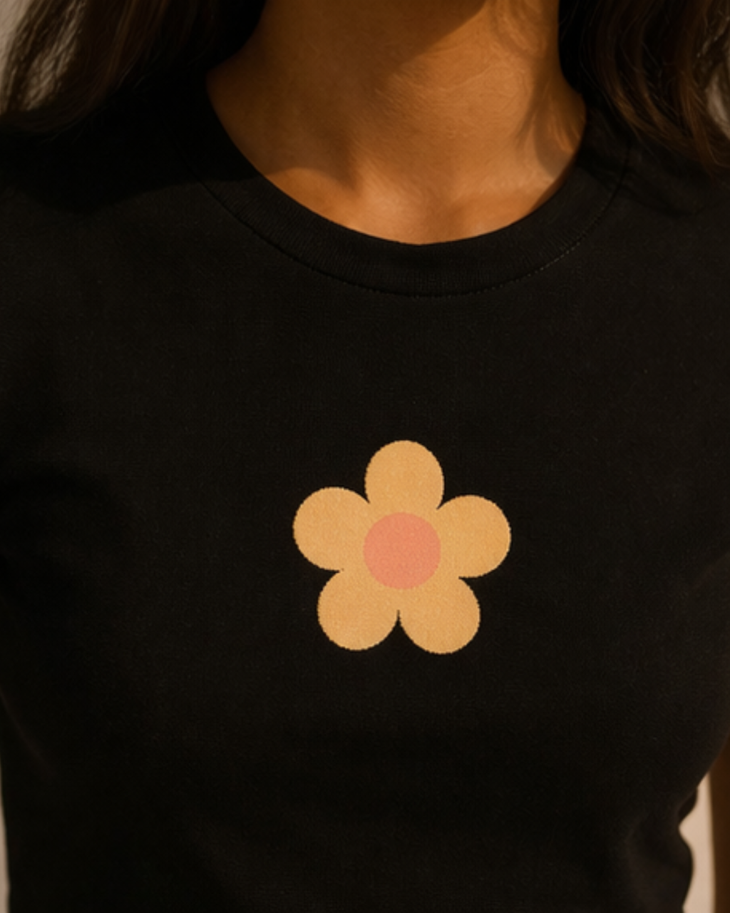 Black t-shirt with a yellow flower design on a person wearing it.