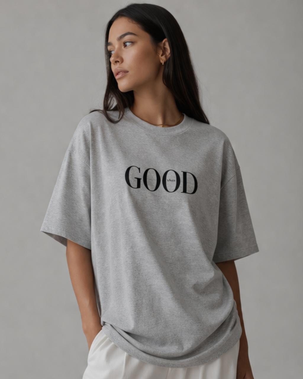 Person wearing a gray t-shirt with 'GOOD' printed on it against a plain background