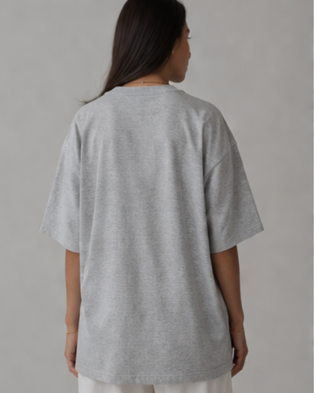 Person wearing a gray oversized t-shirt against a plain background
