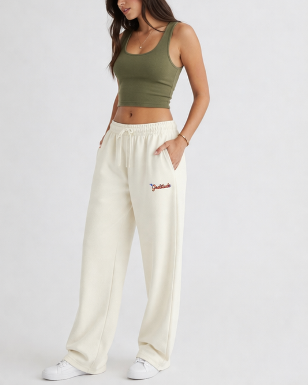 Person wearing a green crop top and cream sweatpants with a logo on a white background