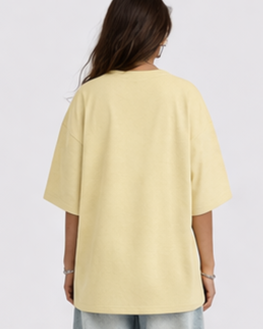 Person wearing a yellow oversized t-shirt on a plain background