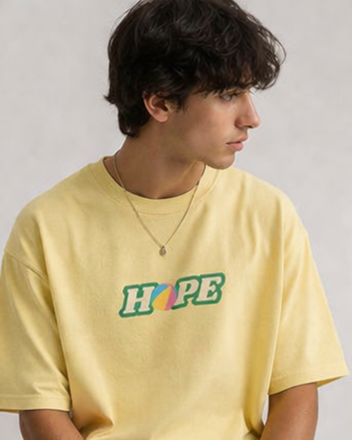 Person wearing a yellow oversized t-shirt with 'HOPE' printed on it against a plain background