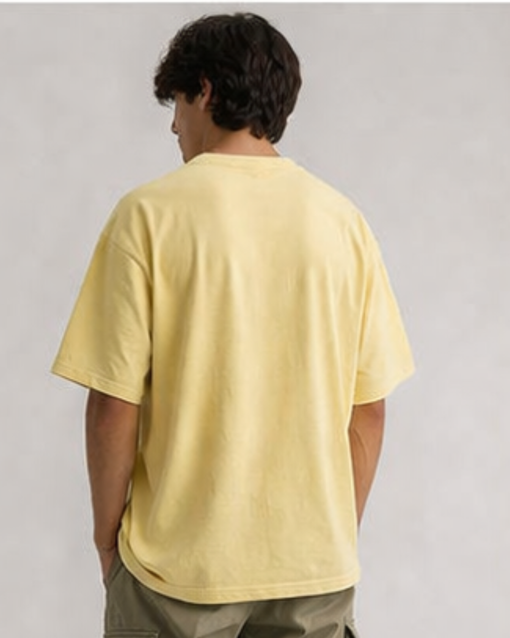 Person wearing a yellow t-shirt against a plain background