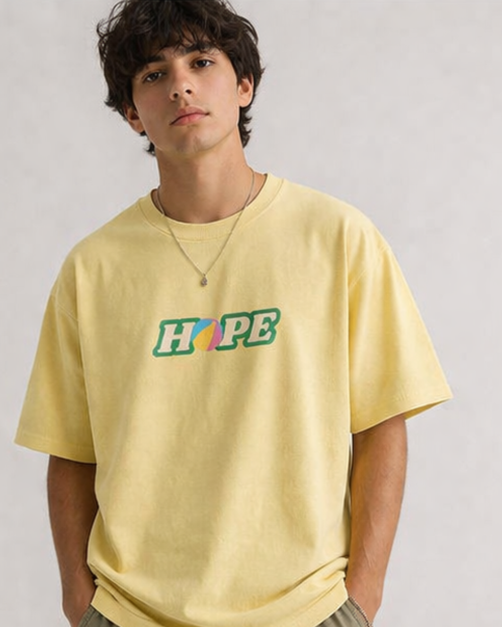 Person wearing a yellow oversized t-shirt with 'HOPE' printed on it against a plain background