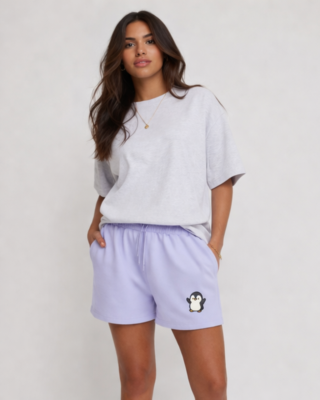 Woman wearing a light gray oversized t-shirt and lavender shorts with a penguin design on a white background