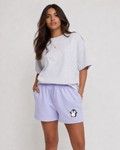 Woman wearing a light gray oversized t-shirt and lavender shorts with a penguin design on a white background
