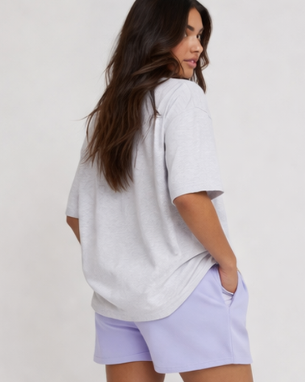 Woman wearing a light gray oversized t-shirt and lavender shorts on a white background